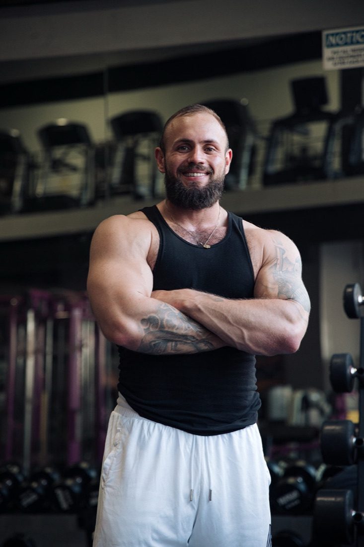 Karel Salajka, trenér Refined Physiques se založenýma rukama v posilovně